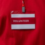 Gros plan d'une étiquette de nom de bénévole accrochée à un cordon rouge, symbolisant le service communautaire.