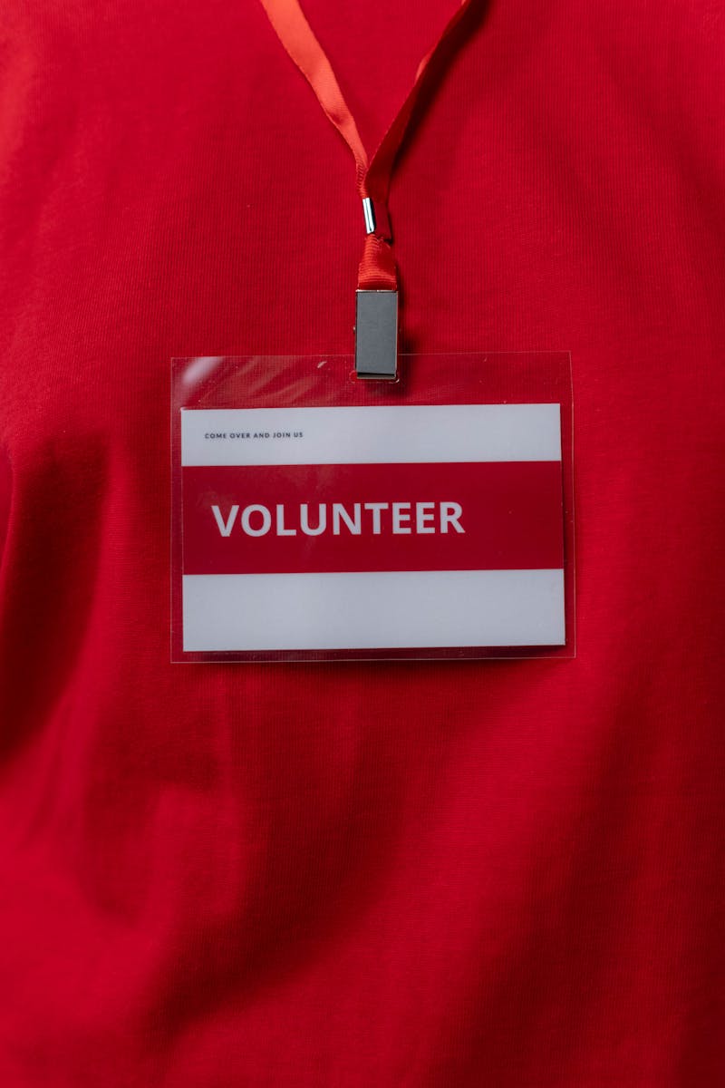 Gros plan d'une étiquette de nom de bénévole accrochée à un cordon rouge, symbolisant le service communautaire.